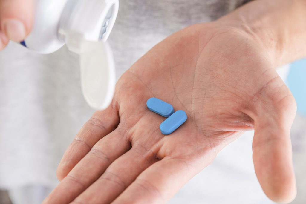An image of a person self-medicating with a blue PrEP pill.