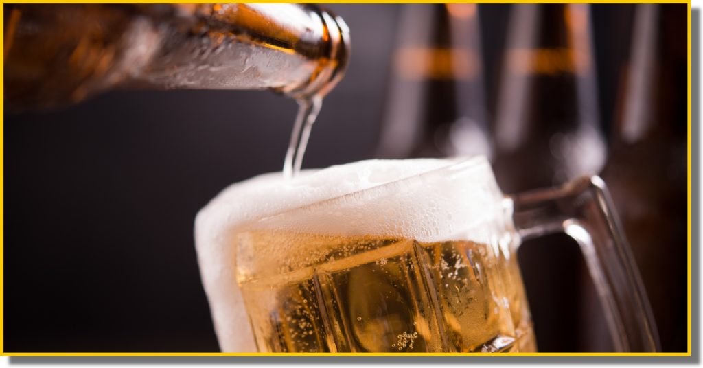A close-up of beer being poured into a clear glass, creating a frothy head at the top.