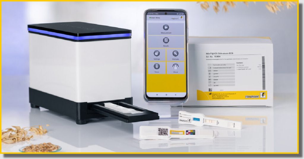 A black and white machine with a box and a smartphone placed next to it alongside product packaging