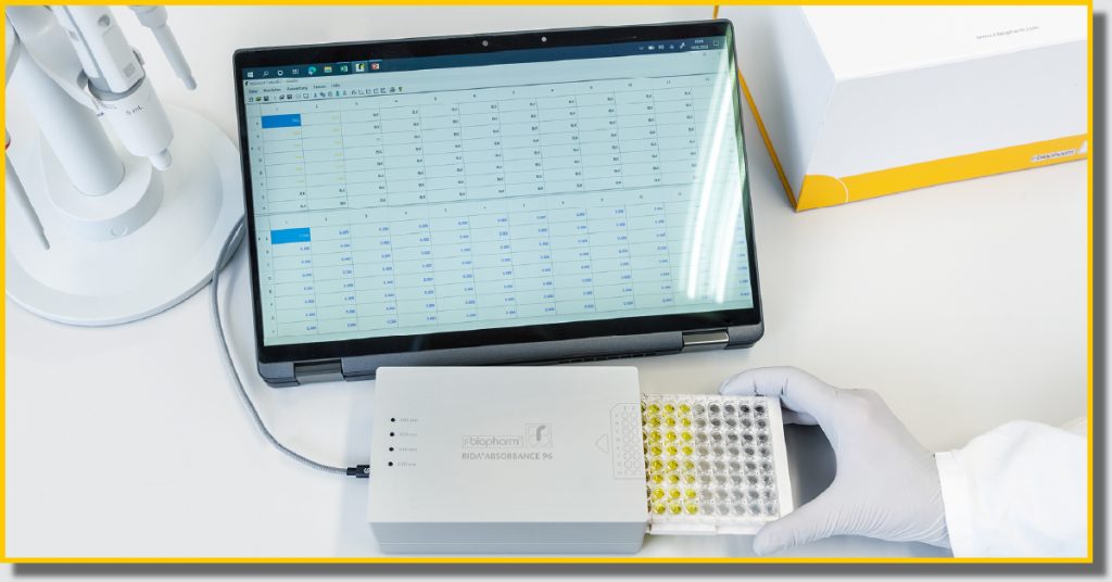 A person sitting at a desk uses a laptop to check the results of scientific analysis.